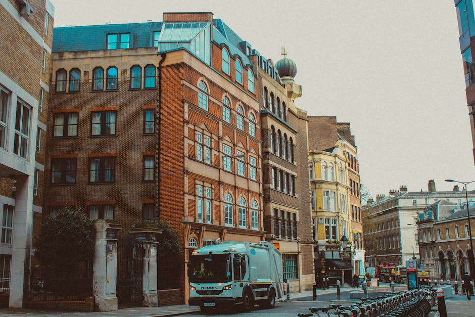 The image depicts a busy street scene with a row of commercial storefronts, including a pharmacy and a seafood shop, in an urban area. In front of these shops, there are numerous pieces of furniture a